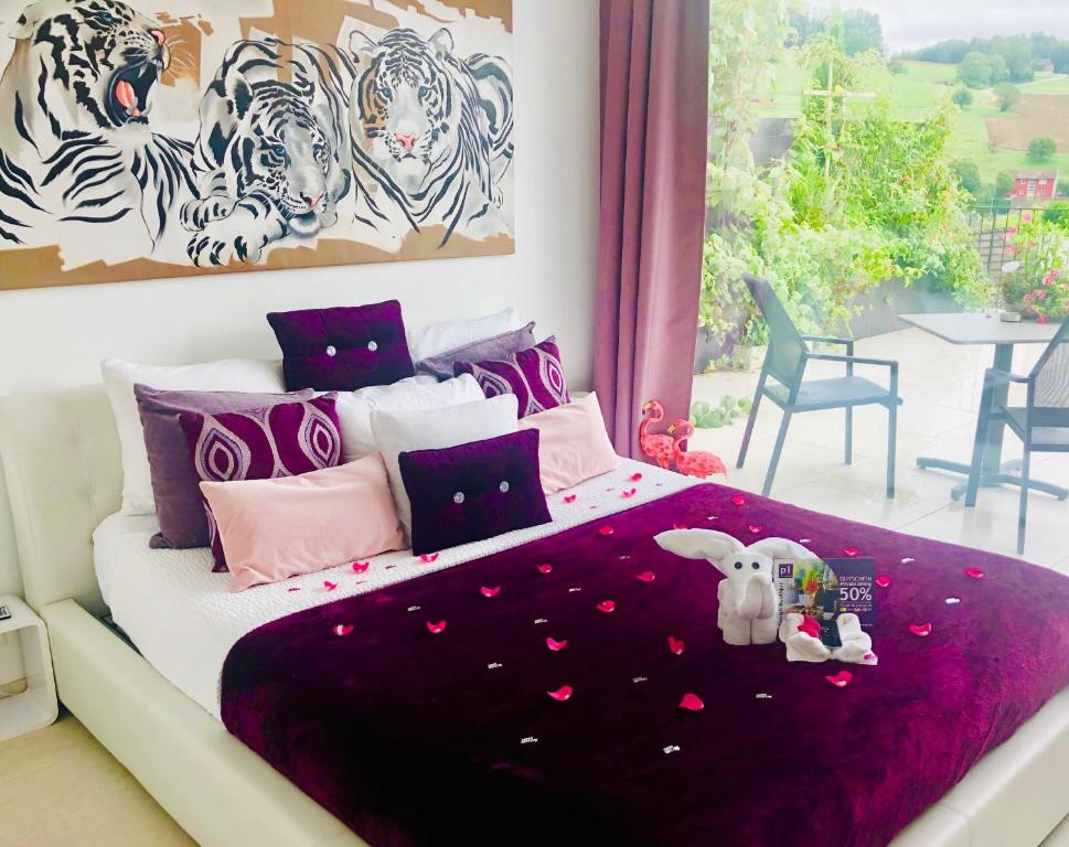een slaapkamer met een bed met een paarse deken bij perfect lifestyle Design Boutique & Private SPA in Gebenstorf