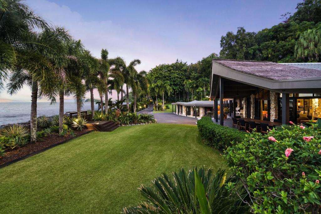 a house with a lawn next to the ocean at Trinity Beach Palace Luxury Estate by Belle Escapes in Trinity Beach