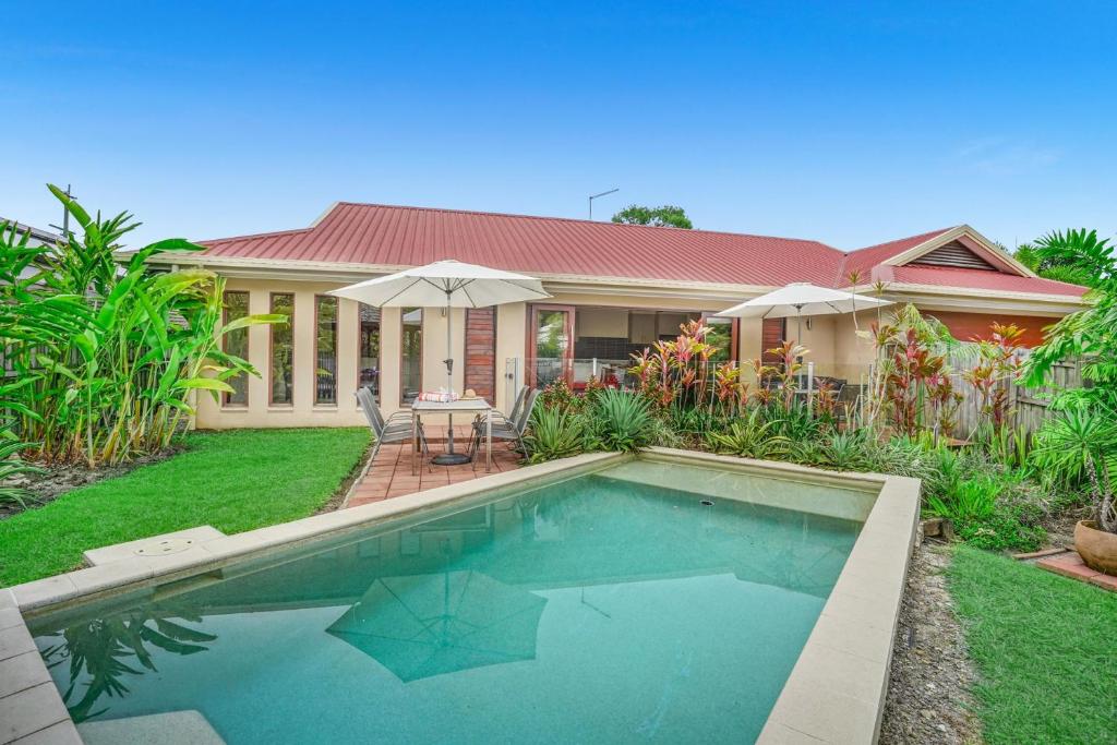 a house with a swimming pool in the yard at Belle Escapes Villa Latania Palm Cove in Palm Cove