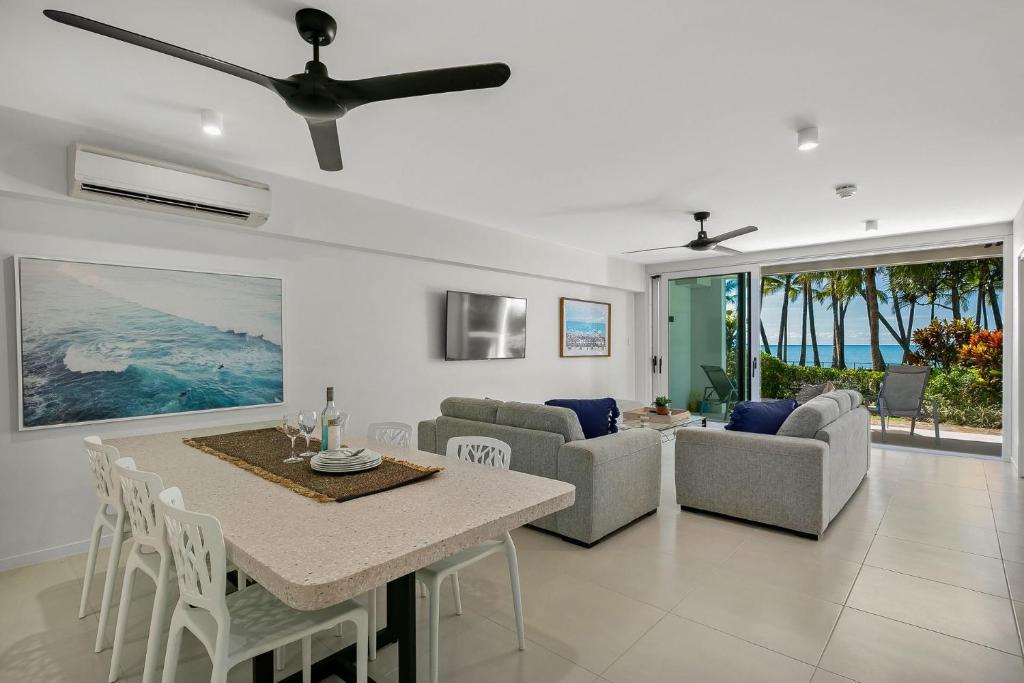 una sala da pranzo e un soggiorno con tavolo e sedie. di Belle Escapes Oceanview Suite 21 Alamanda Palm Cove a Palm Cove