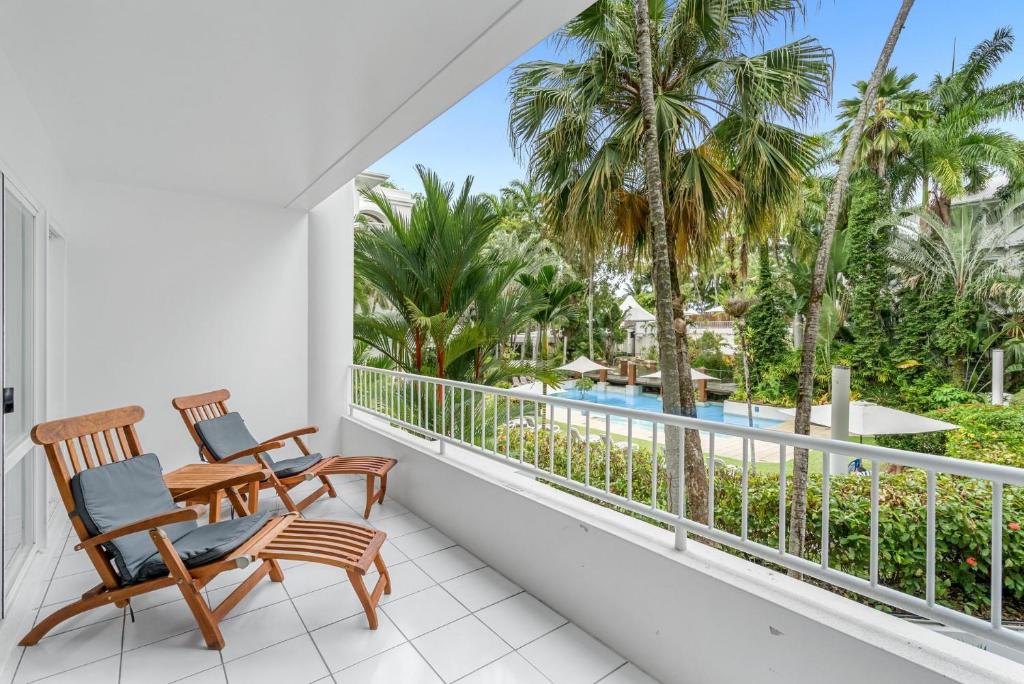 balcón con 2 sillas y vistas a la piscina en Belle Escapes Poolview Suite 74 Alamanda Resort Palm Cove, en Palm Cove
