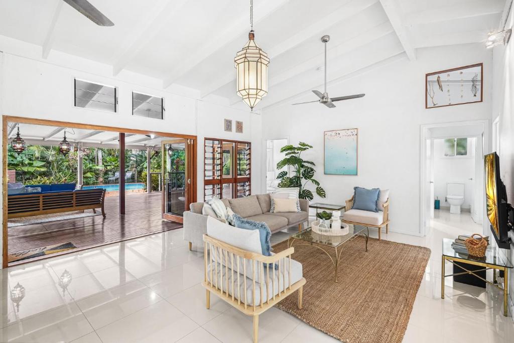 Belle Escapes Tropical Haven Holiday Home Palm Cove في بالم كوف: غرفة معيشة مع أريكة وطاولة