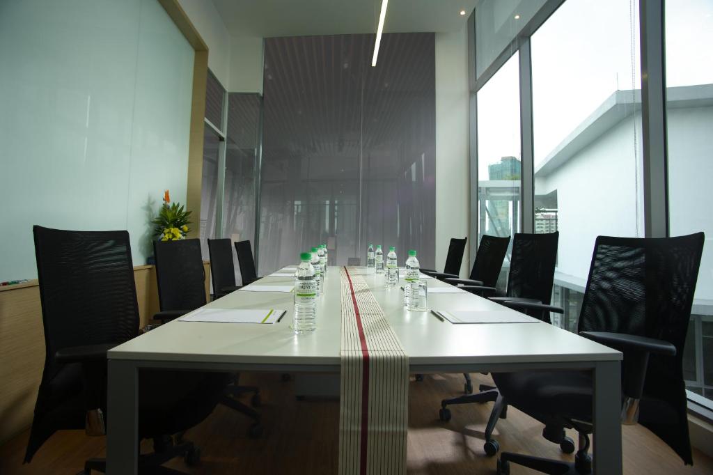 A glass-sided meeting room with a long conference table and office chairs.