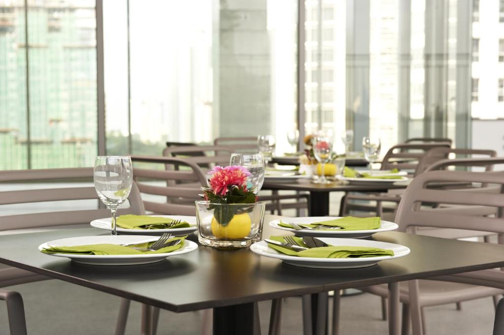 A bright indoor dining area with prepared tables beside floor-to-ceiling windows.