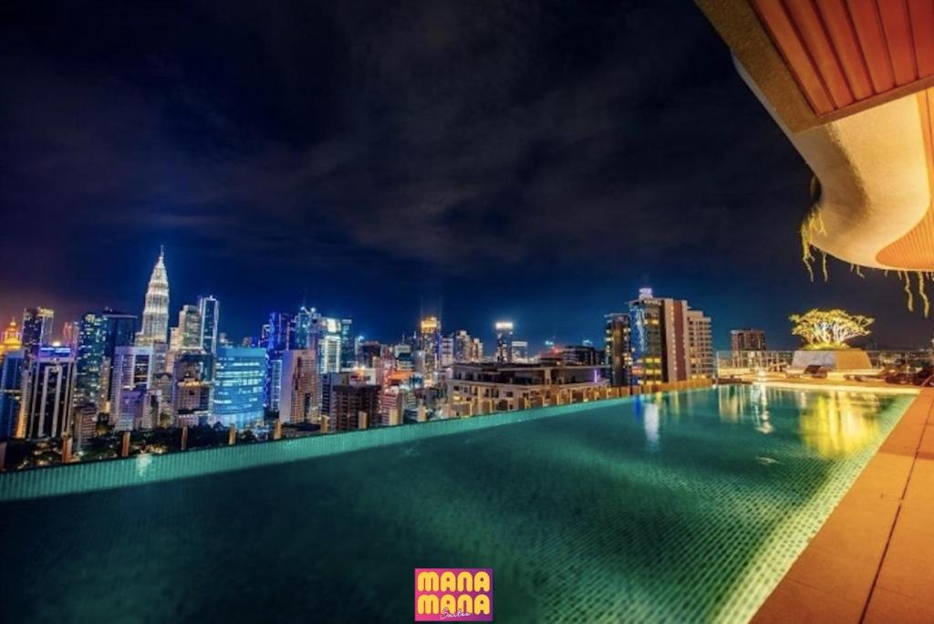 a view of a city skyline at night from a swimming pool at Ceylonz KLCC by Mana-Mana in Kuala Lumpur