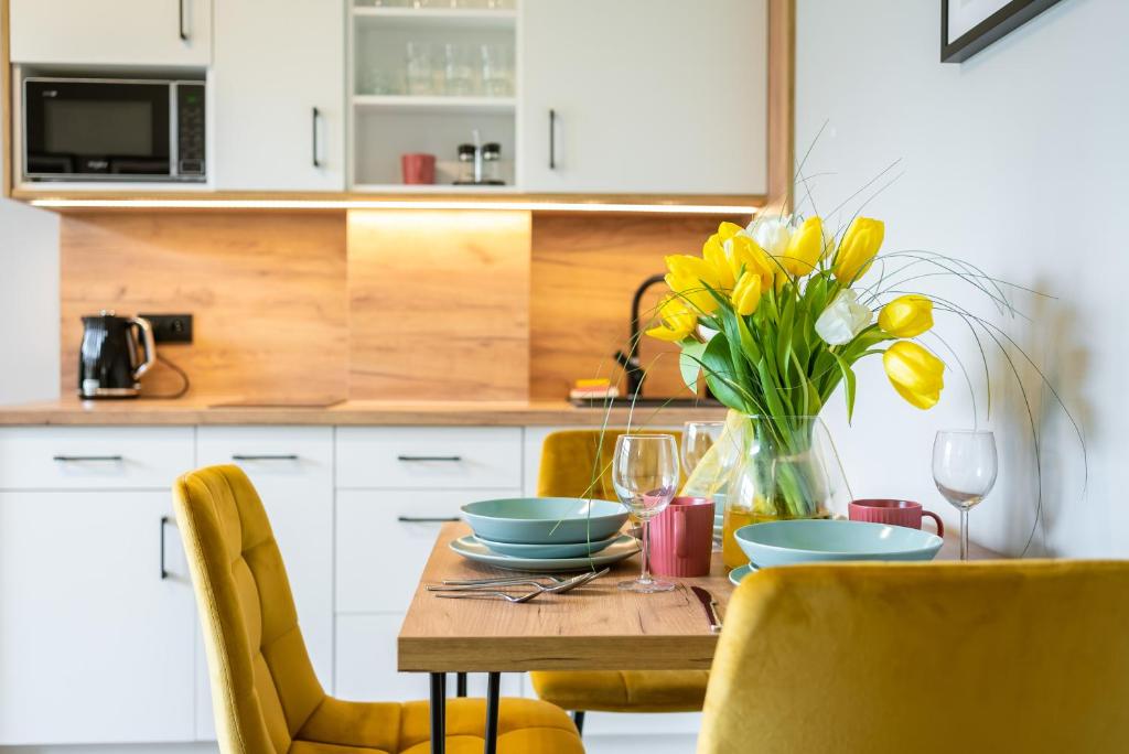 une cuisine avec une table ornée de fleurs jaunes dans un vase dans l'établissement Apartamenty Laguna Beskidów 46 z sauną i siłownią - Dream Apart, à Zarzecze