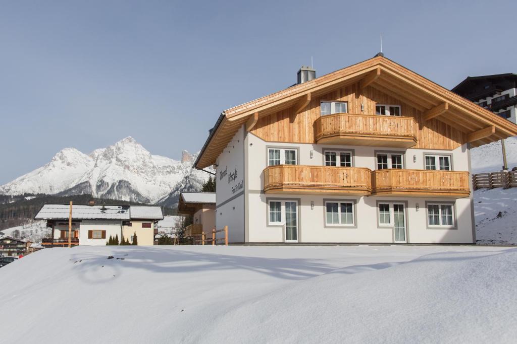 a house in the snow with mountains in the background at Thorau's Lifestyle in Maria Alm am Steinernen Meer