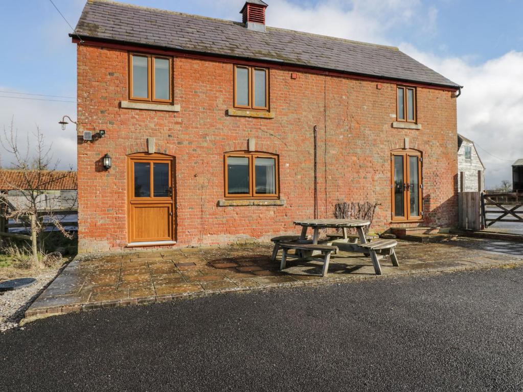a brick house with a picnic table in front of it at Stables Cottage in Melksham