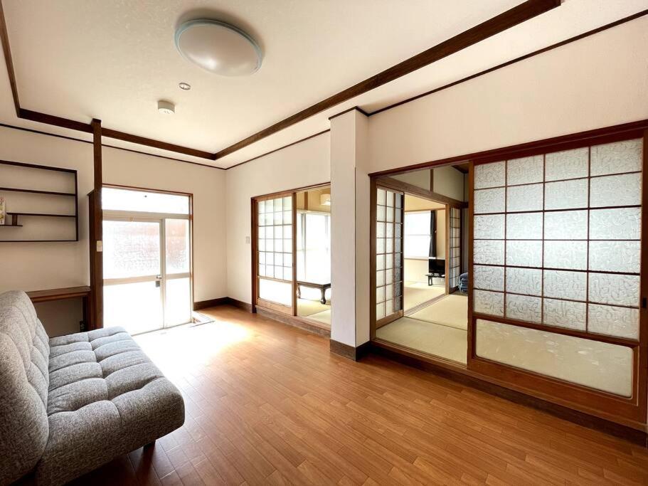 sala de estar con sofá y algunas ventanas en Guest House Koyama -南紀白浜 ゲストハウス 小山- ペット可 en Asso