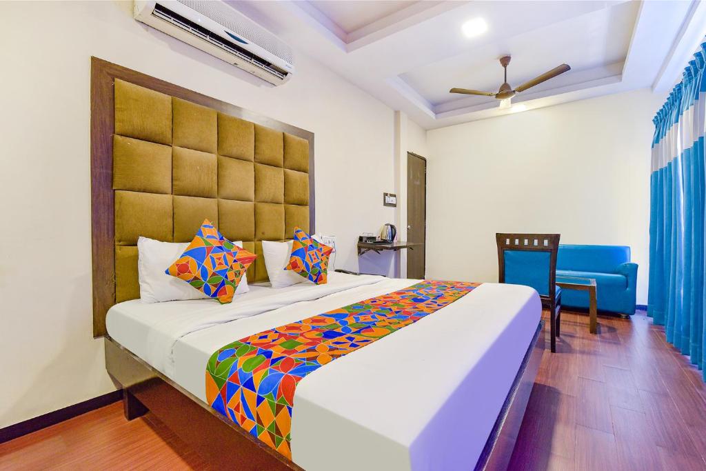 a bedroom with a large bed and a blue chair at FabHotel Telikos Silver, Near Vadodara Airport in Vadodara