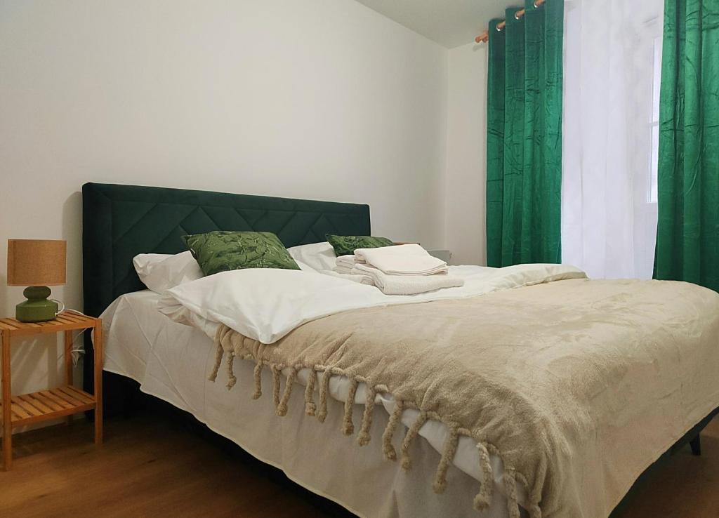 クラクフにあるHugo Eden Apartmentsのベッドルーム1室(緑のカーテン付きの大型ベッド1台付)