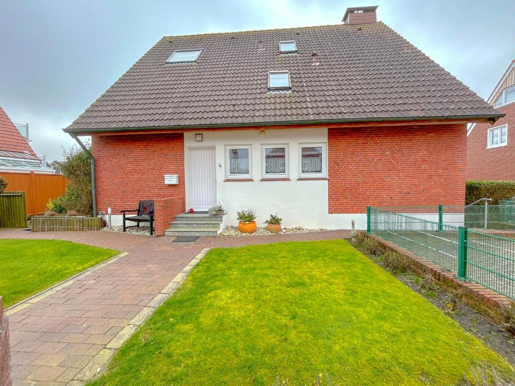 una casa de ladrillo rojo con césped delante en Haus Kleemann en Norderney