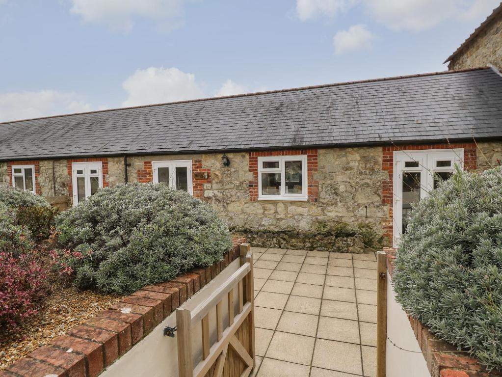 a stone house with a fence and bushes at Dairy Cottage in Newport