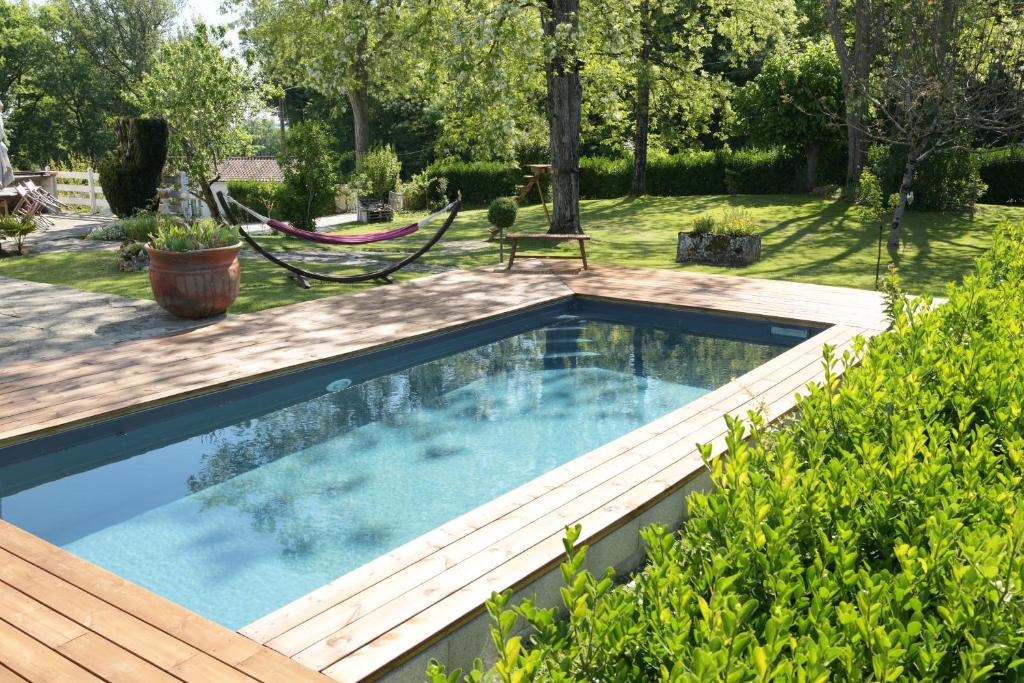 une piscine dans un jardin avec une terrasse en bois dans l'établissement l'Orée du Bois, à Saint-Brice