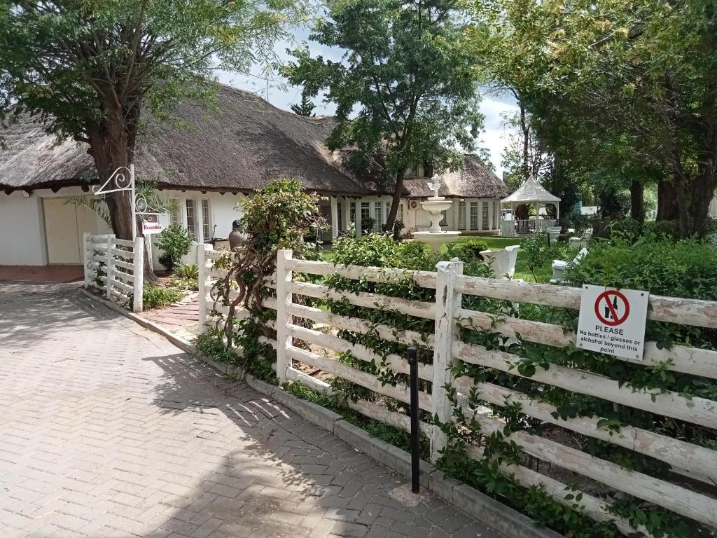 ein weißer Zaun ohne Fahrradschild vor einem Haus in der Unterkunft THATCH HAVEN GUEST HOUSE in Mahikeng