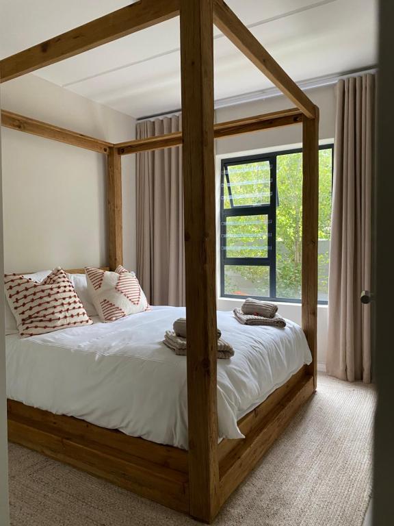 a wooden canopy bed in a bedroom with a window at Villa Granito No 6, Paarl in Paarl