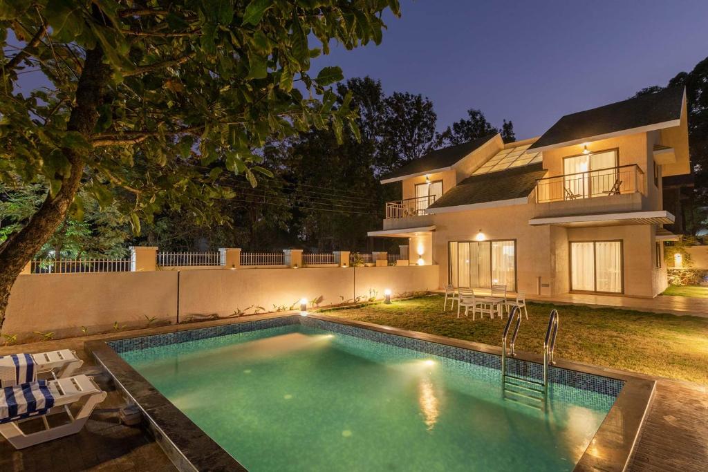 a house with a swimming pool in front of a house at StayVista's Enchanting Haven - Modern Interiors, Sprawling Lawn with Gazebo, Swimming Pool, Indoor Games in Panchgani
