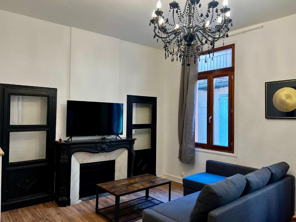 a living room with a couch and a tv and a chandelier at République :Appartement T3 Centre historique in Perpignan