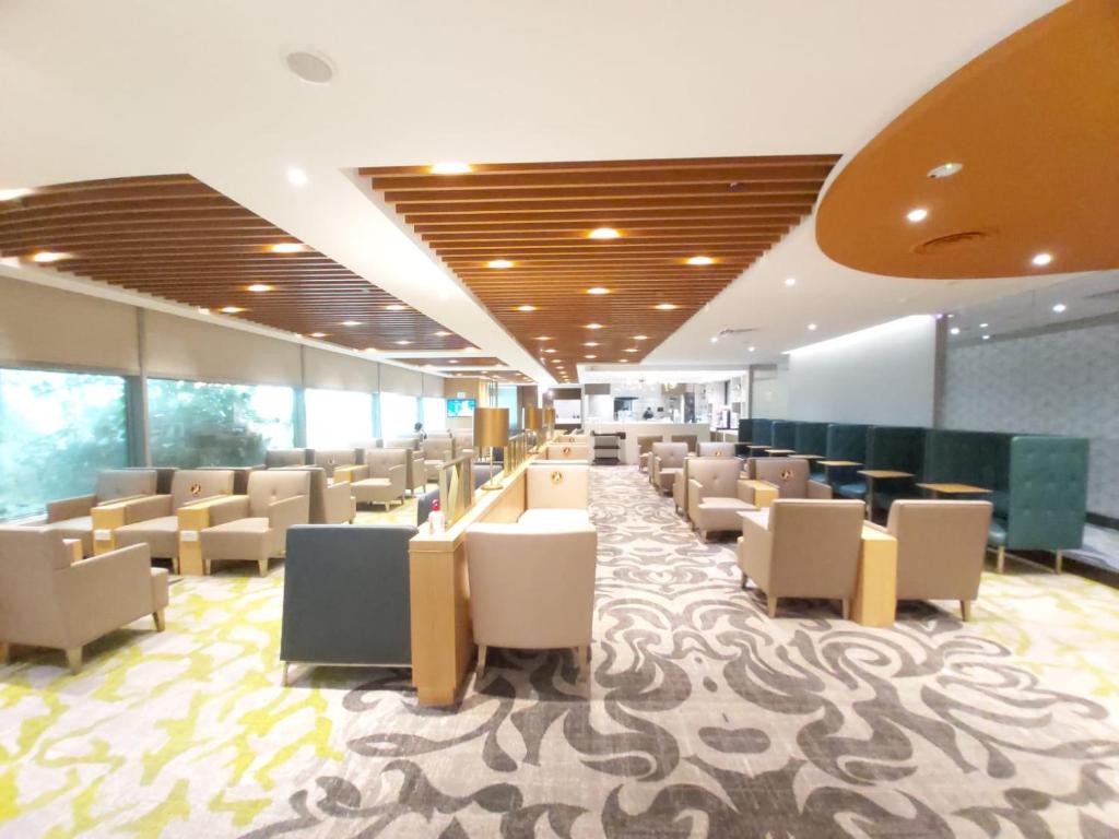 uma sala de espera com cadeiras e mesas num edifício em Ambassador Transit Lounge Terminal 3 em Singapura