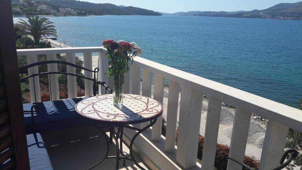 eine Vase mit Blumen auf einem Tisch auf einem Balkon in der Unterkunft Antonia Apartments in Trogir