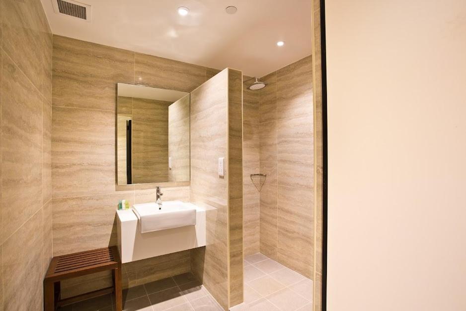 La salle de bains est pourvue d'un lavabo et d'un miroir. dans l'établissement Ambassador Transit Lounge Terminal 2, à Singapour
