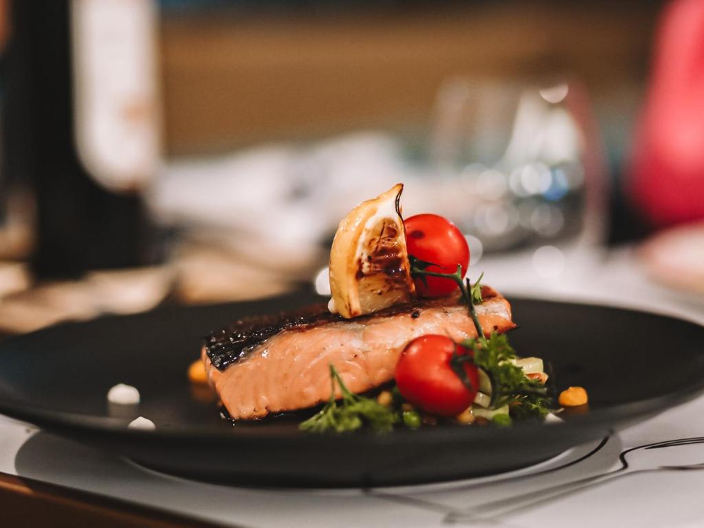 a black plate with a piece of meat and vegetables at Hotel Millennium by Aycon in Budva