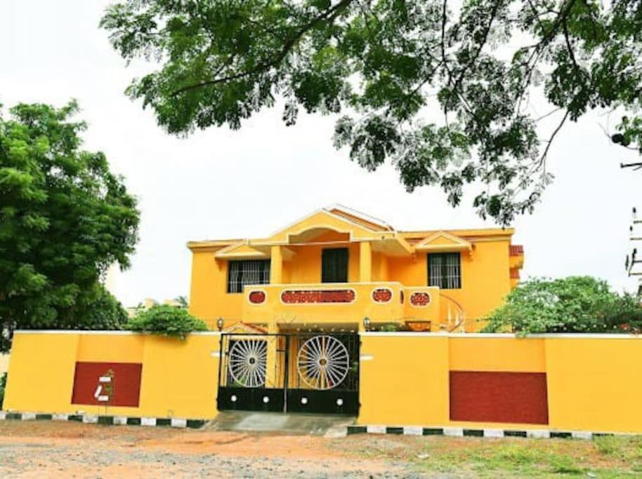 a yellow house with a fence in front of it at Smith 5BHK Villa in Puducherry