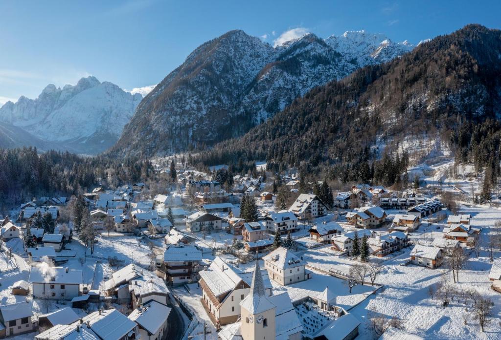 ein schneebedecktes Dorf mit Bergen im Hintergrund in der Unterkunft Valbruna Inn Bed & Breakfast in Valbruna