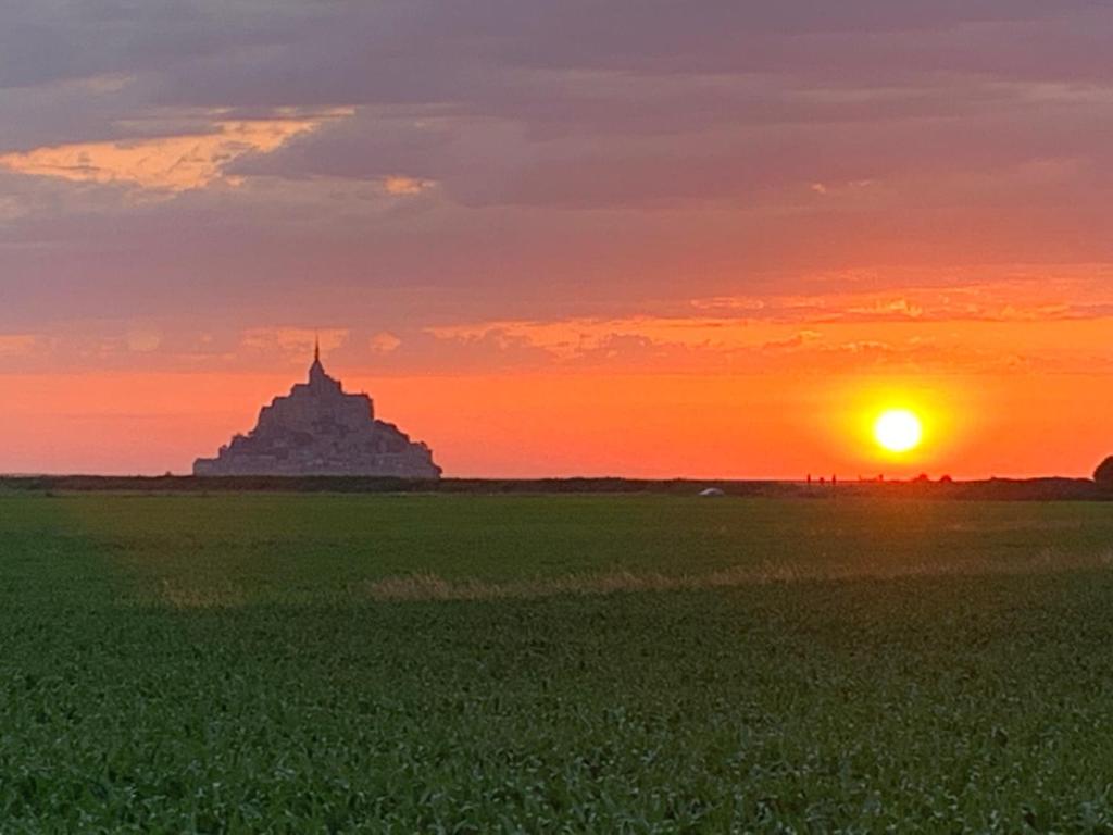 un tramonto su un campo verde con un edificio sullo sfondo di Rue Veillon a Céaux