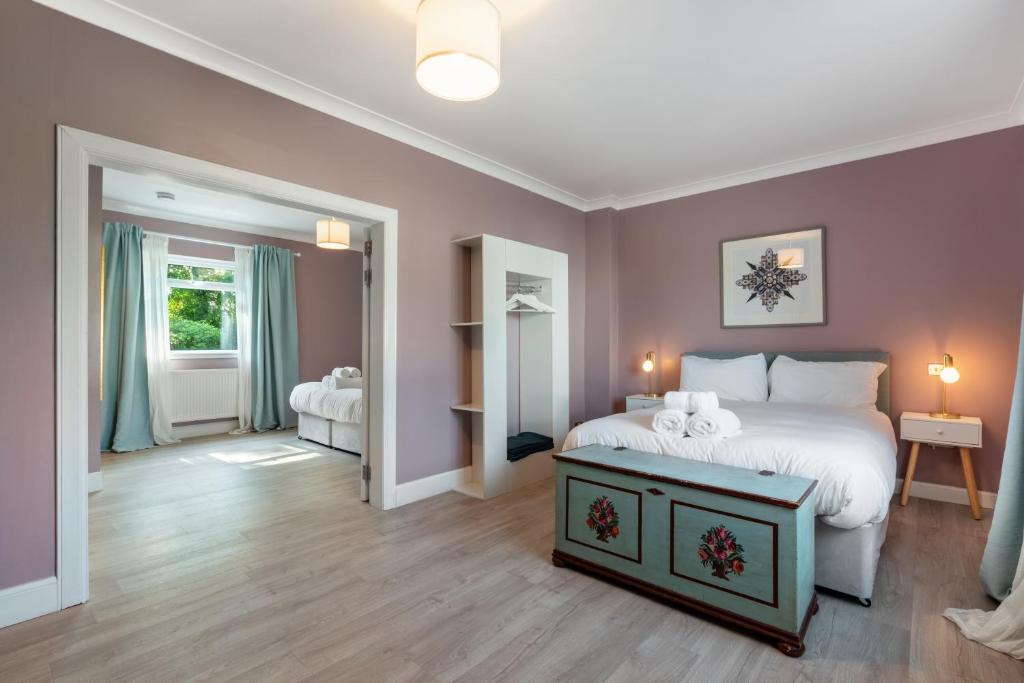 Un dormitorio con una cama blanca y una habitación con paredes rosas. en Stylish 2 bedroom Cottage near Glasgow Airport en Lochwinnoch