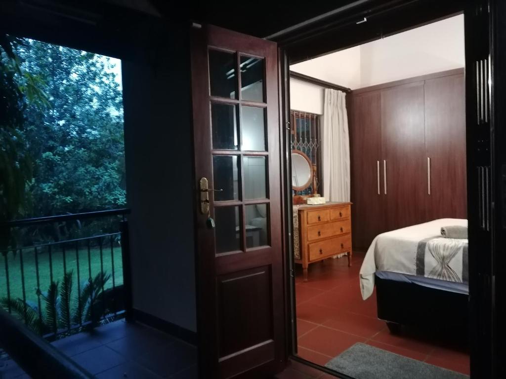 1 dormitorio con una puerta que conduce a una cama y un balcón en Luxury Room - Sielevreugde, en Modimolle