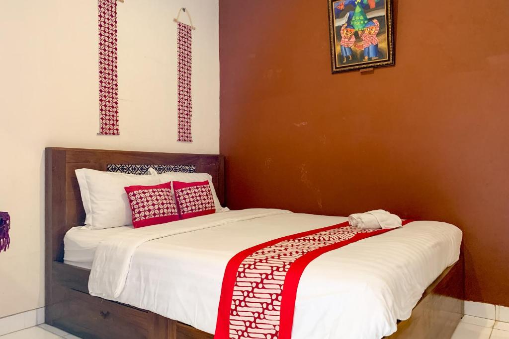 a bedroom with two beds with red and white pillows at Grha Vege Jawi Syariah Mitra RedDoorz in Yogyakarta