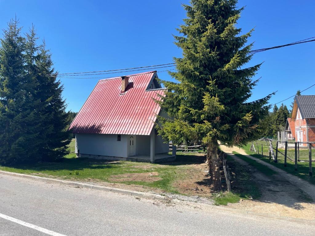 una casa con techo rojo junto a un árbol en Vikendica Golija, en Novi Pazar