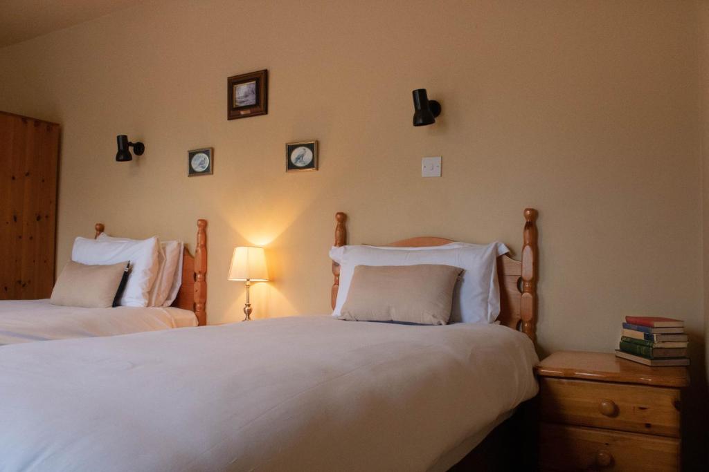 a bedroom with two beds and a lamp and pictures on the wall at Atlantic View Cottages in Doolin