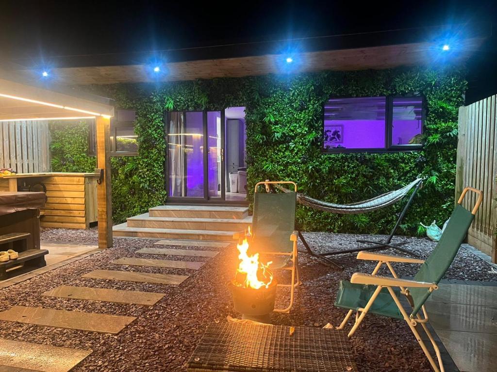 a fire pit with a hammock and a chair in a backyard at night at Hazells Lodge Farm Stay Sleeps 2 Hottub Pool Table at Ayrshire Rural Retreats in Galston