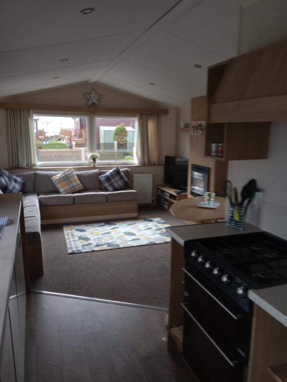 cocina y sala de estar con sofá y fogones en D24 is a 2 bedroom 6 berth caravan close to the beach on Whitehouse Leisure Park in Towyn near Rhyl with decking and private parking space This is a pet free caravan, en Abergele