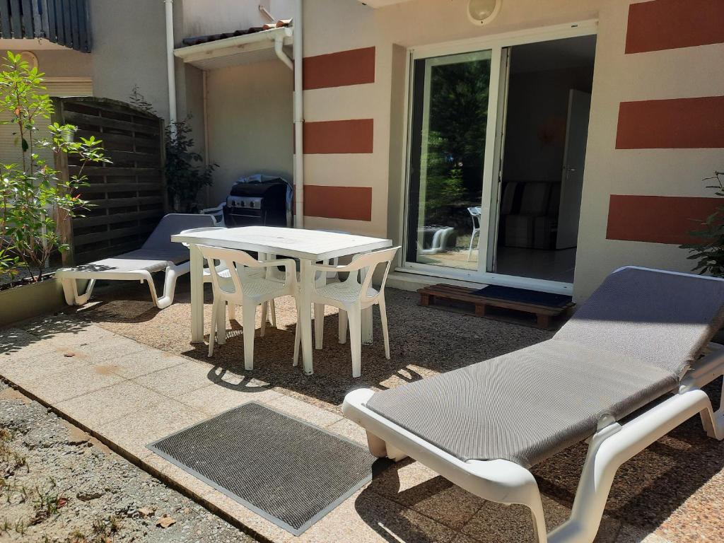 une table et des chaises assises à l'extérieur d'une maison dans l'établissement Belle maisonnette dans résidence avec piscine, à Soulac-sur-Mer