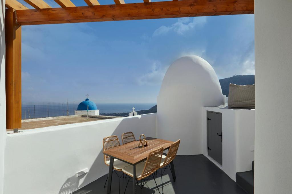 un tavolino e delle sedie su un balcone con vista sull'oceano di Aecon Suites a Éxo Goniá