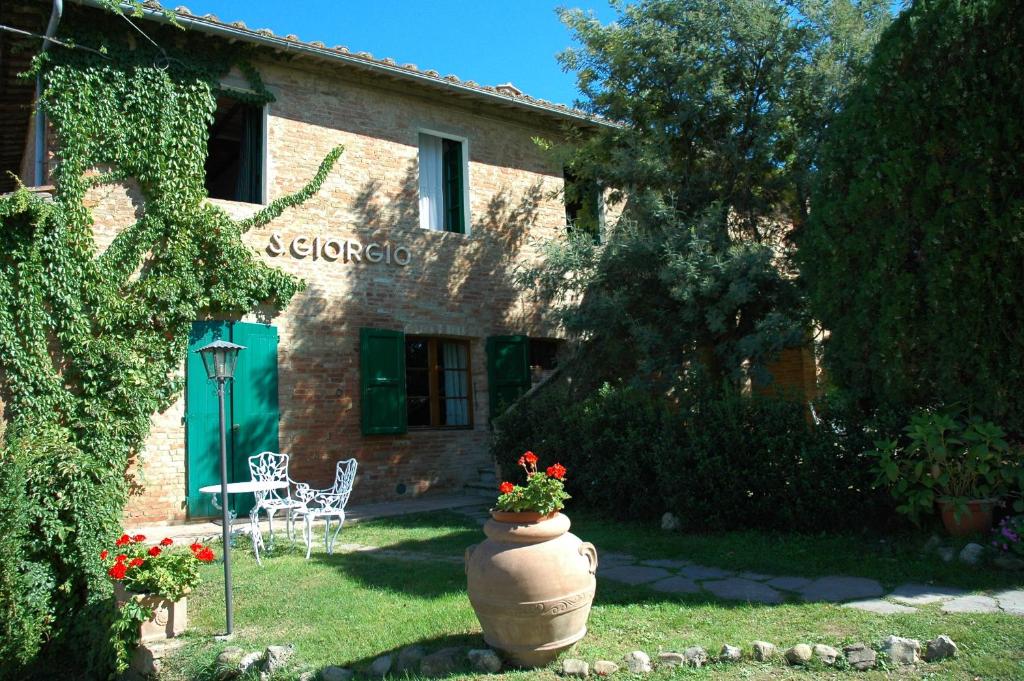 eine große Vase mit Blumen vor einem Haus in der Unterkunft Agriturismo San Giorgio in Monteroni dʼArbia