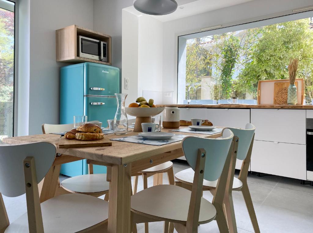 een keuken met een houten tafel met stoelen en een blauwe koelkast bij Appartement Océane - Villas Lake and Sea in Seignosse
