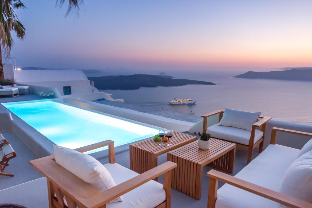 ein Schwimmbecken mit Stühlen und einem Tisch in der Unterkunft Villa Aura in Firostefani