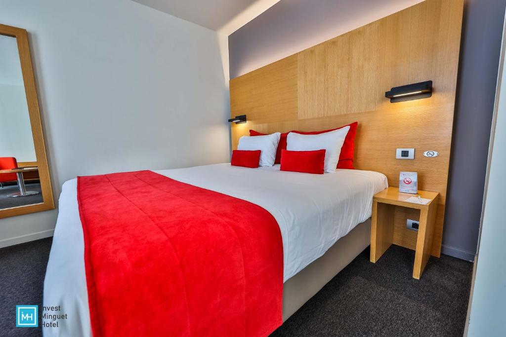 a hotel room with a large bed with red pillows at Hotel De La Couronne Liege in Liège