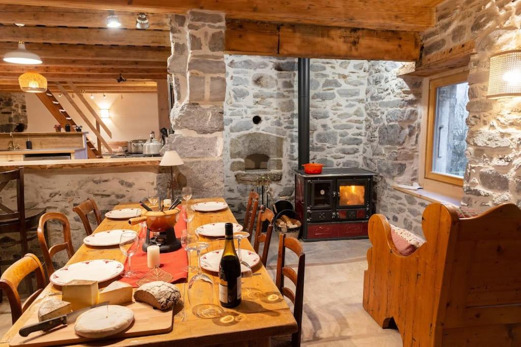 een eetkamer met een tafel en een stenen open haard bij Gîte ferme en permaculture avec ses animaux in Sixt