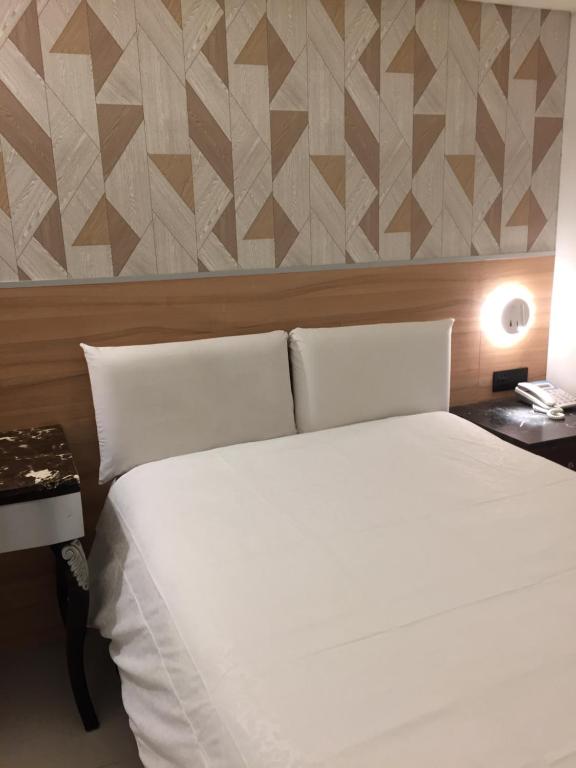 Un dormitorio con una gran cama blanca y una pared en Ji Pin Hotel, en Xinzhuang