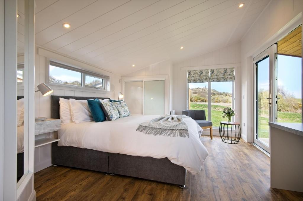 a bedroom with a large bed and large windows at The Pond Lodges Barstobrick in Ringford