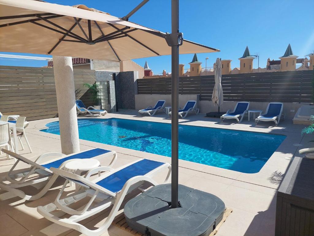 a swimming pool with lounge chairs and an umbrella at Villa Perla - Puerto de Mazarron in Puerto de Mazarrón