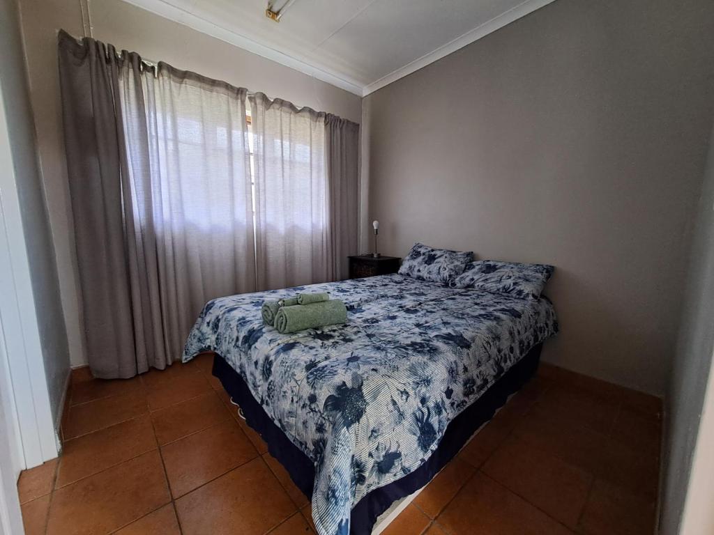 a bedroom with a bed with a blue and white blanket at Woodhills Guest house in Piet Retief
