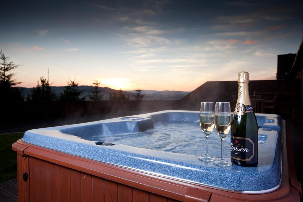 a bottle of champagne and two wine glasses in a hot tub at Cherry Blossom Cottage in Cupar