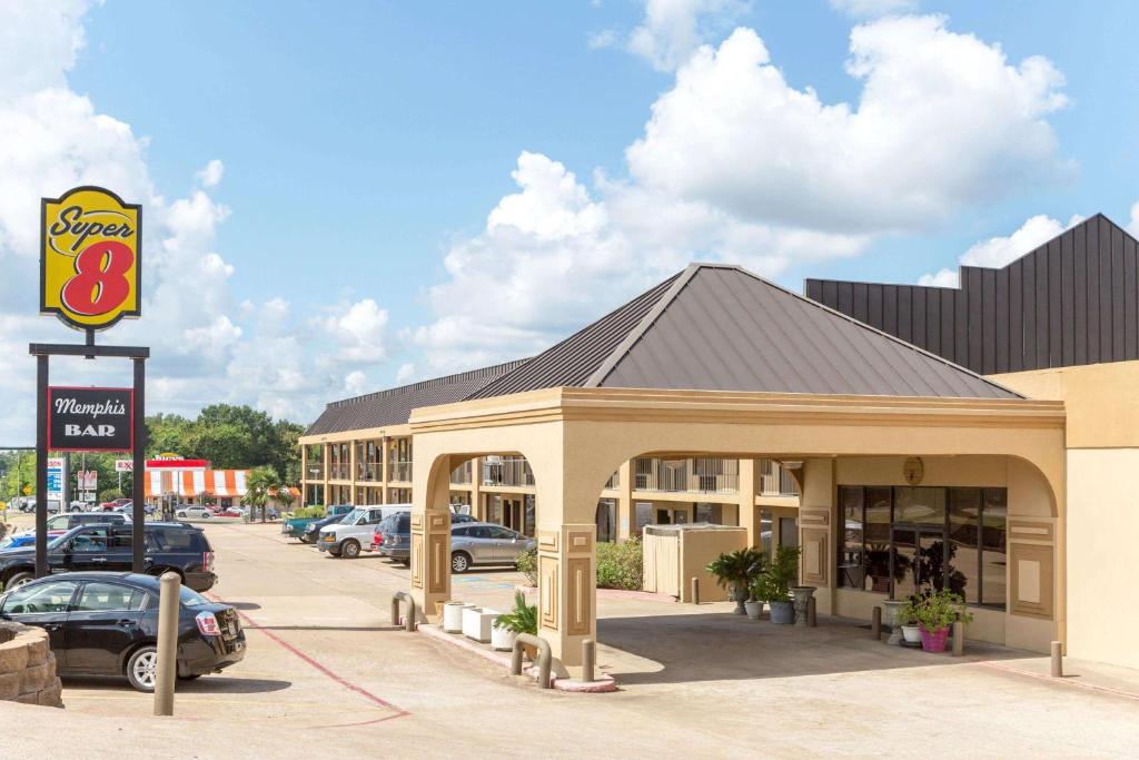 a building with a gas station with cars parked in a parking lot at Super 8 by Wyndham Longview/North in Longview