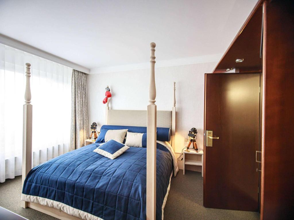 a bedroom with a bed with a blue comforter at Mercure Hotel Riesa Dresden Elbland in Riesa